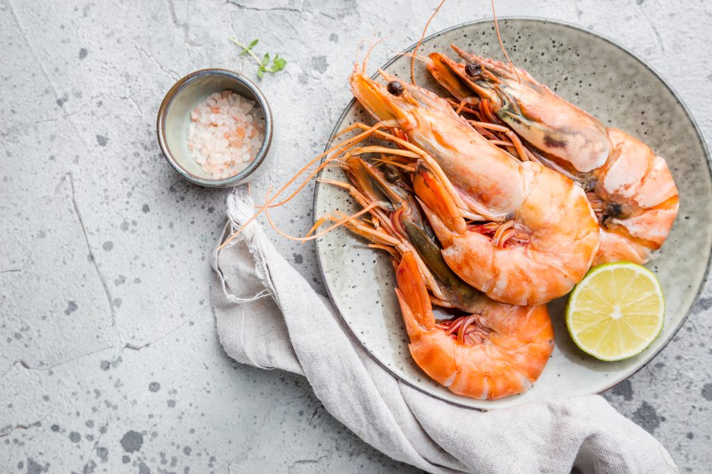 A white bowl filled with fresh prawns, showcasing their pink color and curved shape.