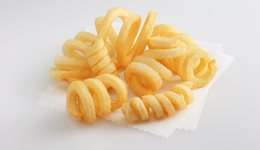 Curly french fries arranged in a stack displayed on a white surface.