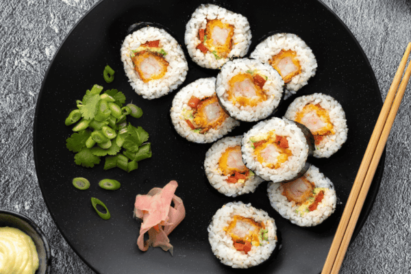 Sushi rolls filled with succulent shrimp, neatly arranged on a white plate, garnished with pickled ginger and wasabi.