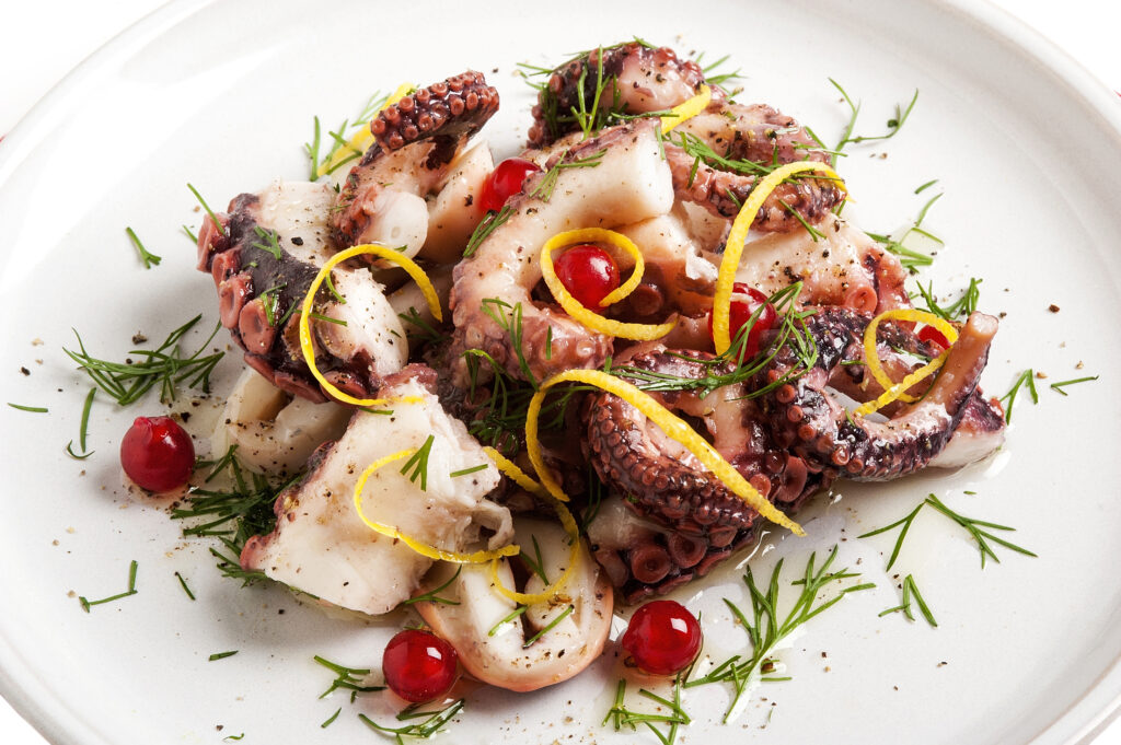 Freshly blanched octopus tentacles arranged on a white plate
