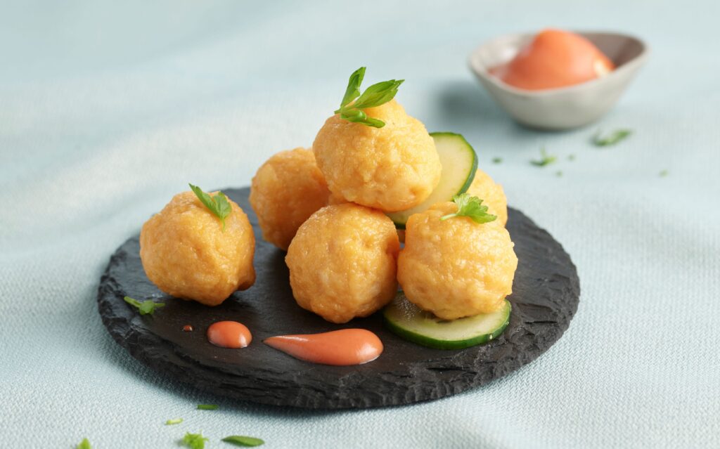 Prawn balls arranged on a white plate, showcasing their golden-brown exterior and juicy prawn filling.